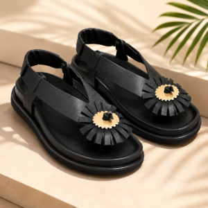 Sandales plates-formes noires de style Padam avec une grande fleur décorative en relief sur le dessus et une bride arrière.